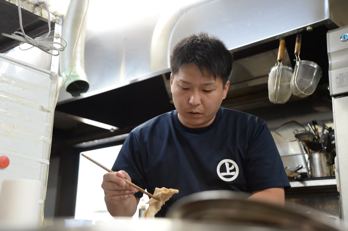 厨房で調理する村上泰輝さん